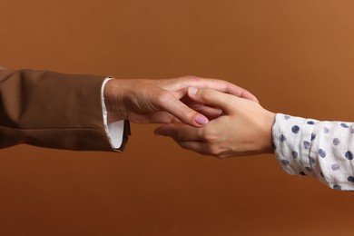 Photo of Women shaking hands on brown background, closeup