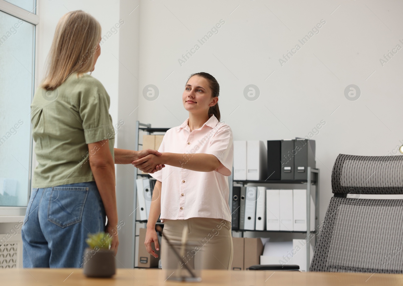 Photo of Cooperation and teamwork. Women shaking hands in office