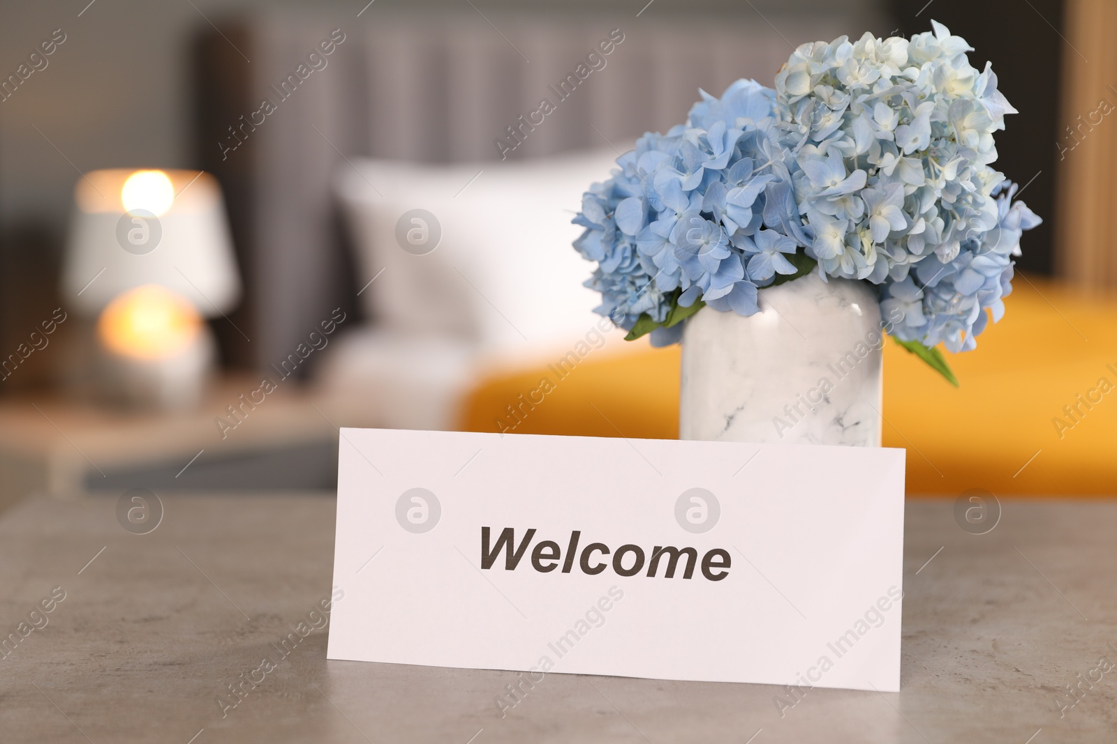 Photo of Card with word Welcome and hydrangea flowers on grey table indoors