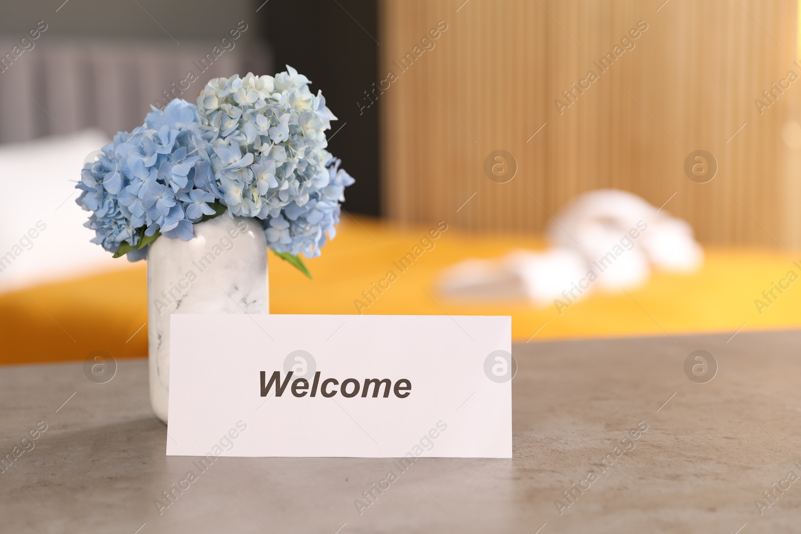 Photo of Card with word Welcome and hydrangea flowers on grey table indoors