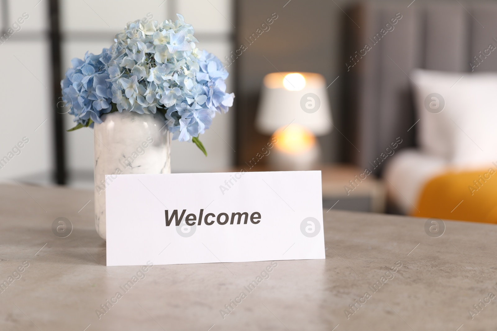 Photo of Card with word Welcome and hydrangea flowers on grey table indoors