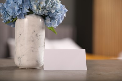 Photo of Welcome. Blank card and hydrangea flowers on grey table indoors, closeup