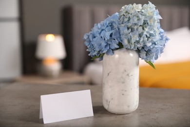 Photo of Welcome. Blank card and hydrangea flowers on grey table indoors