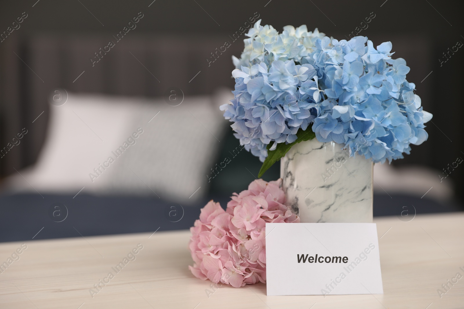 Photo of Card with word Welcome and hydrangea flowers on wooden table, space for text