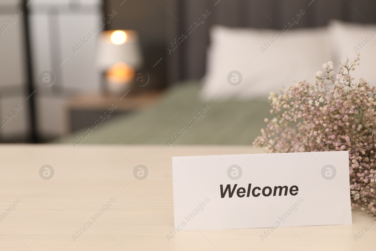 Card with word Welcome and gypsophila flowers on wooden table indoors, closeup. Space for text Photo of Card with word Welcome and gypsophila flowers on wooden table indoors, closeup. Space for text