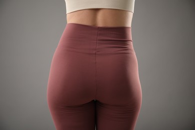 Photo of Woman wearing sports leggings on grey background, closeup
