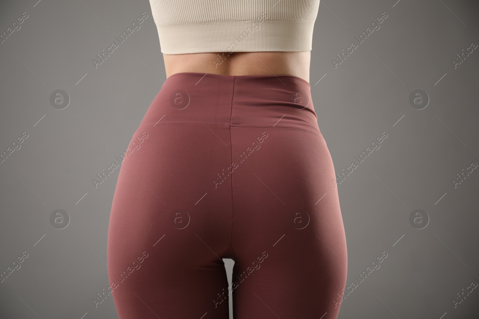 Photo of Woman wearing sports leggings on grey background, closeup