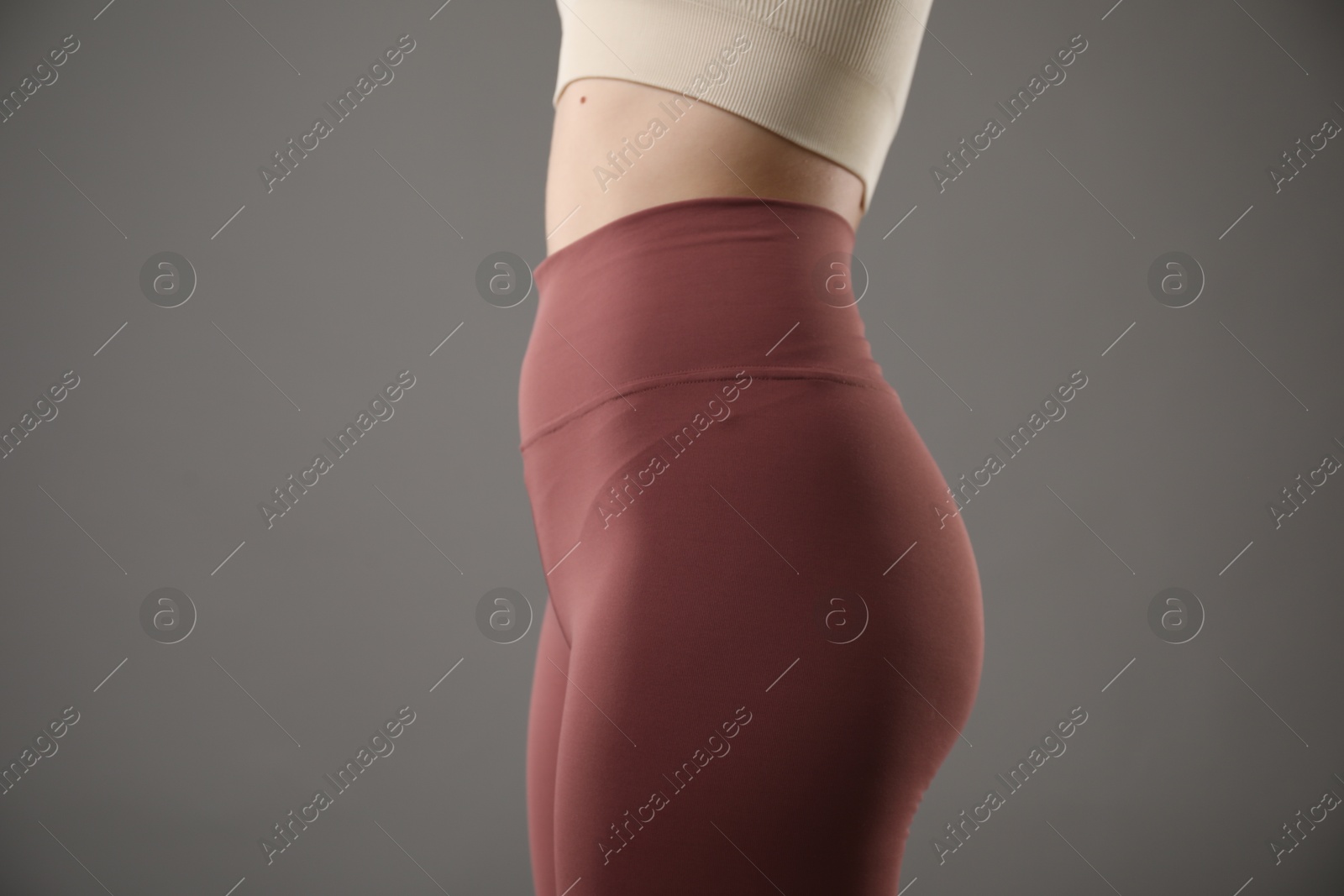 Woman in sportswear on grey background, closeup Photo of Woman in sportswear on grey background, closeup