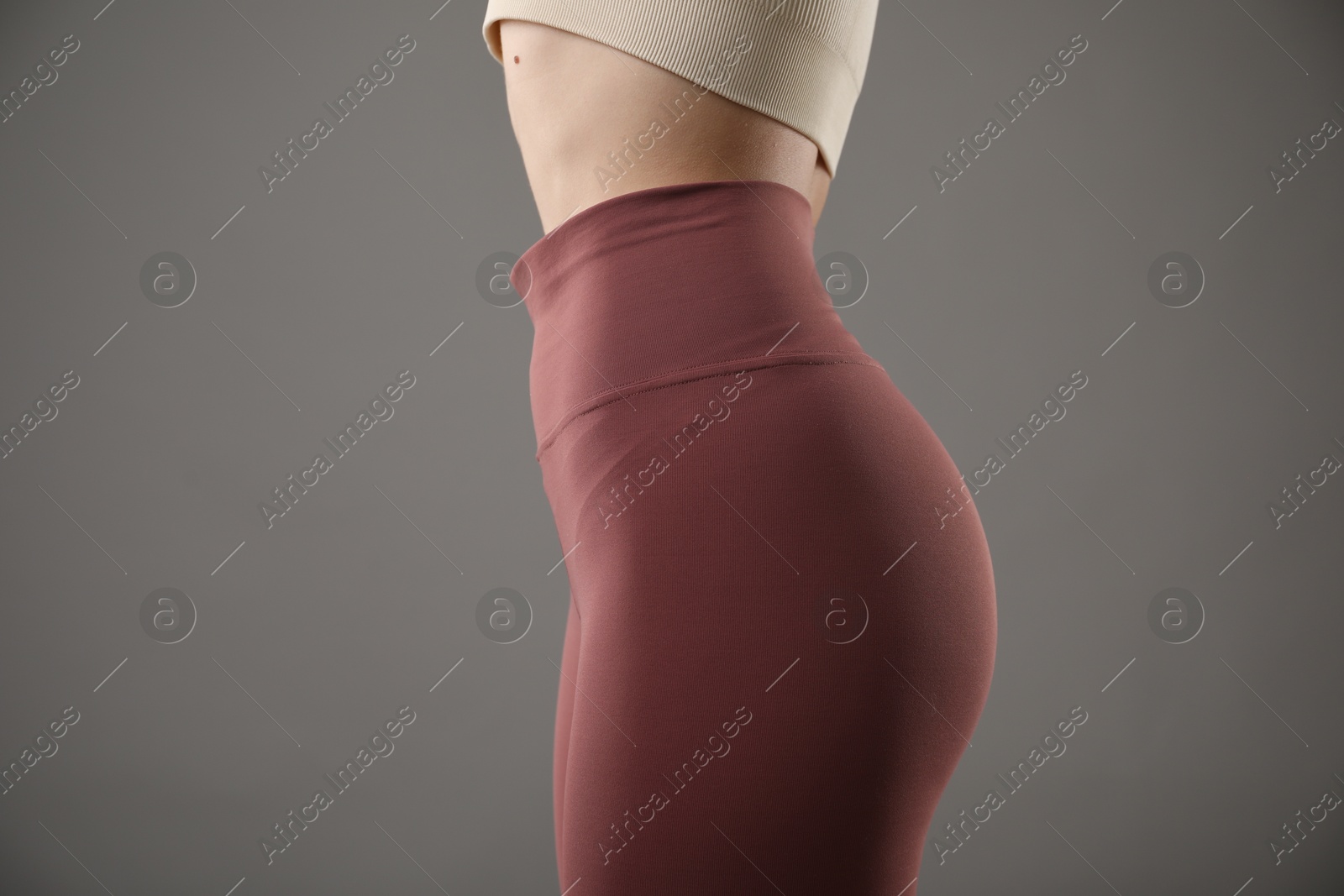 Woman in sportswear on grey background, closeup Photo of Woman in sportswear on grey background, closeup