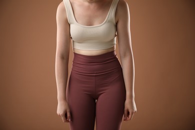Photo of Woman with bad posture on brown background, closeup