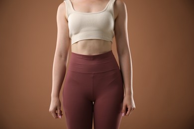 Photo of Woman in sportswear on brown background, closeup