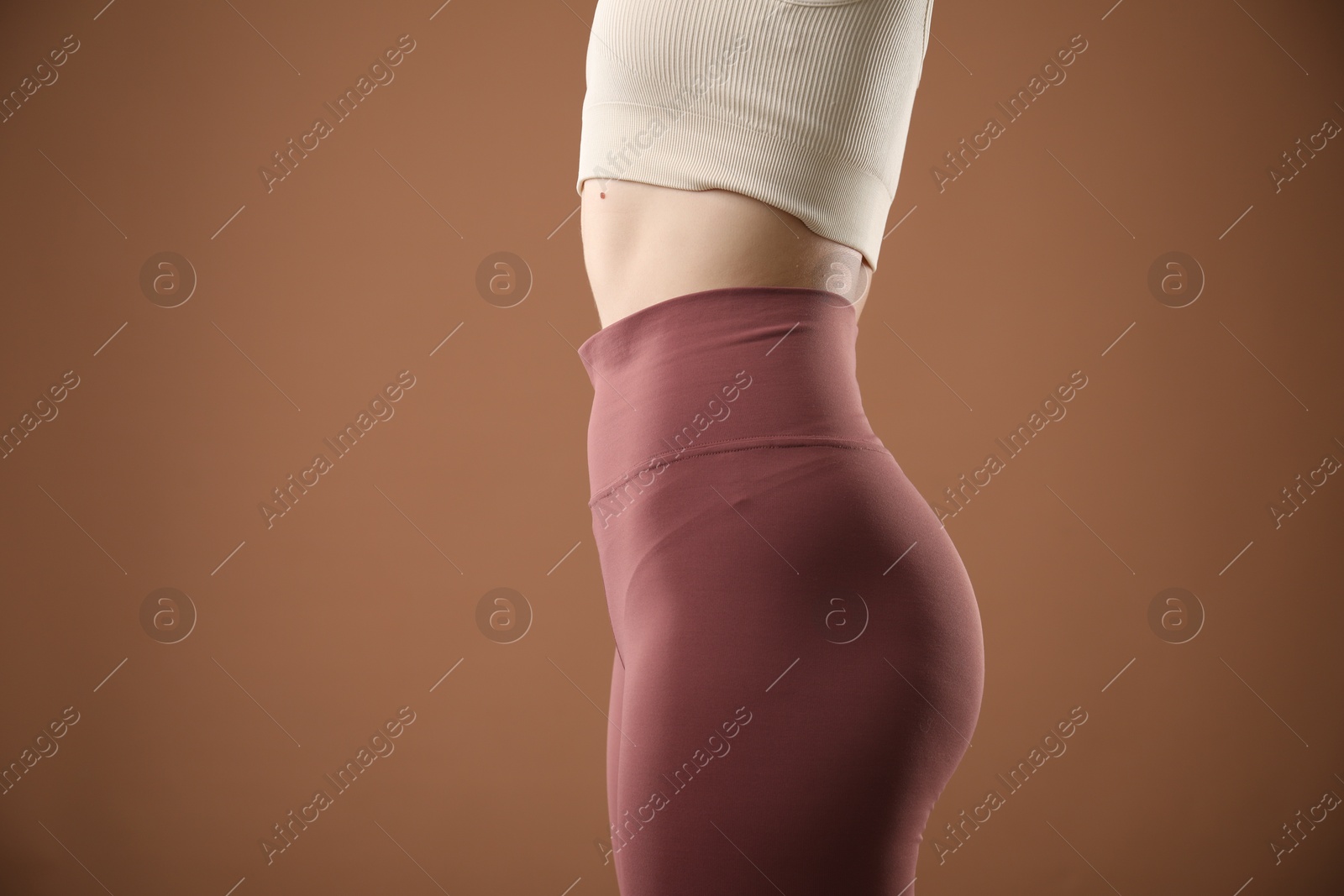 Photo of Woman in sportswear on brown background, closeup