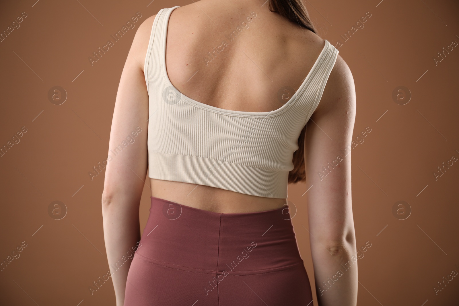 Woman with bad posture on brown background, closeup Photo of Woman with bad posture on brown background, closeup