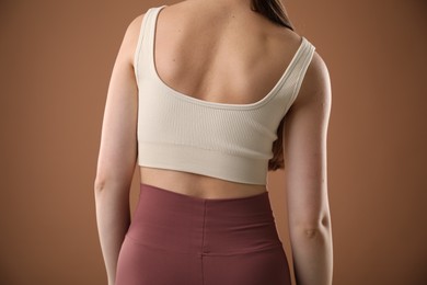 Photo of Woman with bad posture on brown background, closeup