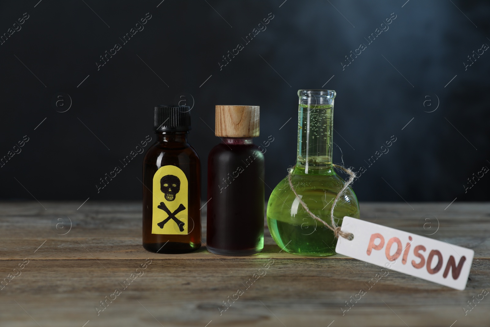 Bottles of poisons with warning sign on wooden table against dark background with smoke Photo of Bottles of poisons with warning sign on wooden table against dark background with smoke