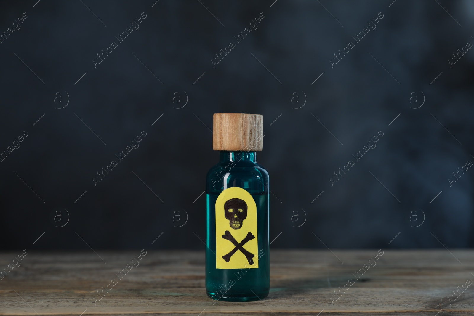 Photo of Bottle of poison with warning sign on wooden table against dark background with smoke