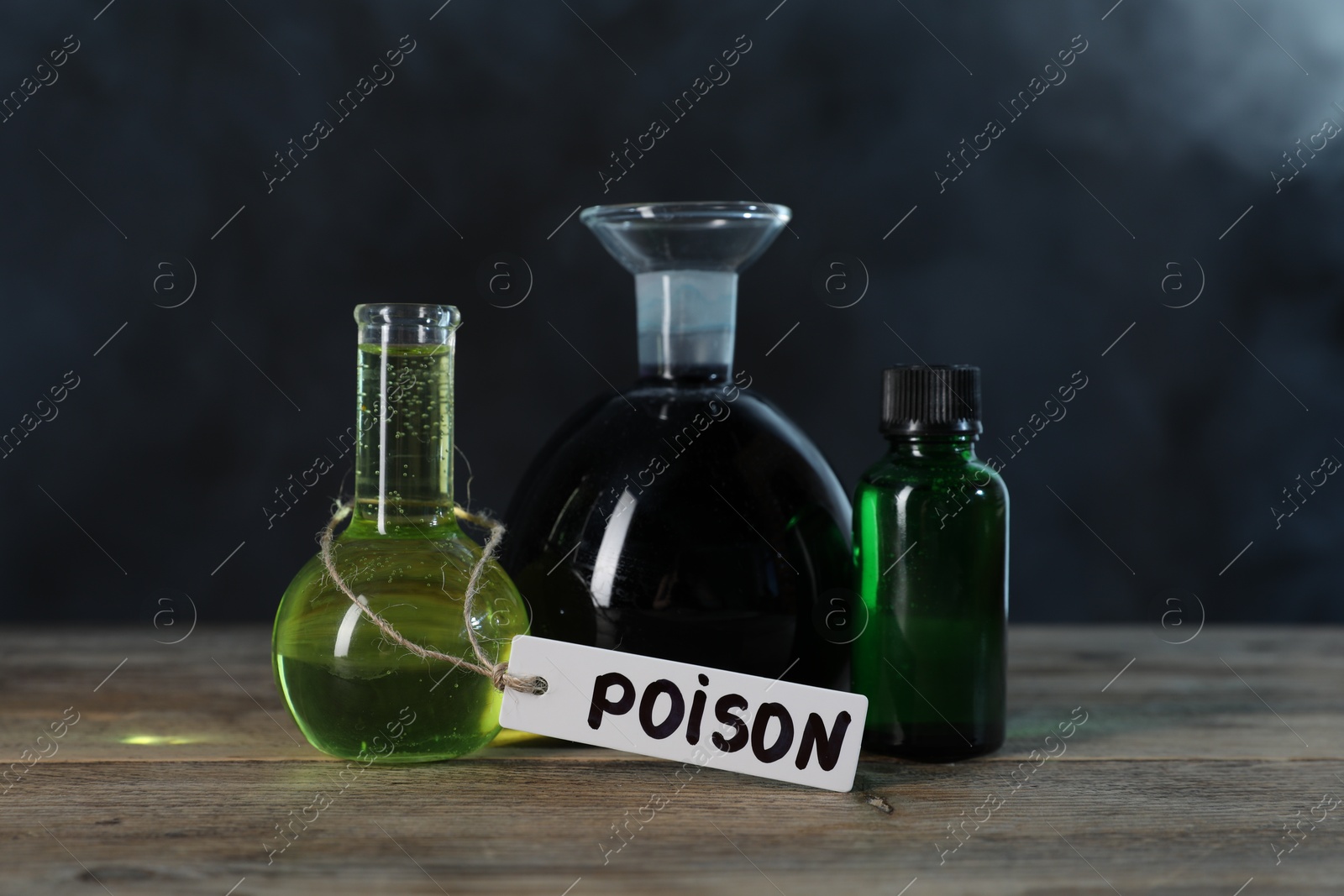 Bottles with poisons on wooden table against dark background with smoke Photo of Bottles with poisons on wooden table against dark background with smoke
