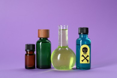 Photo of Bottles of poisons with warning sign on violet background