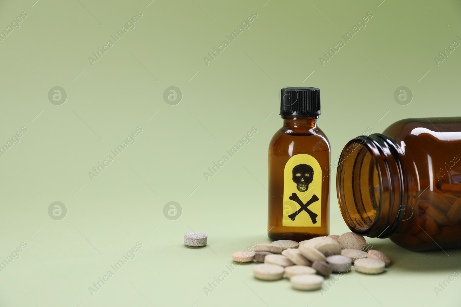 Photo of Bottles of poisons with warning sign on pale olive background, closeup. Space for text