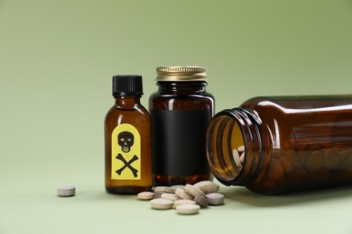 Photo of Bottles of poisons with warning sign on pale olive background, closeup