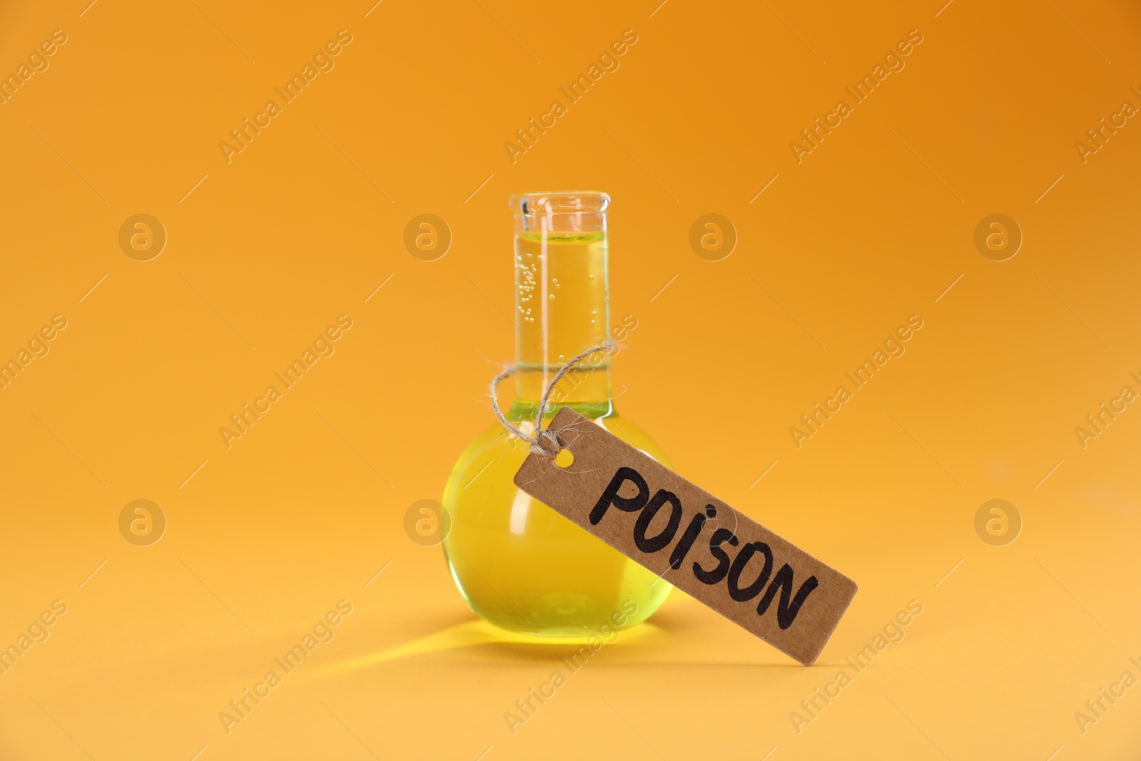 Glass flask with poison on orange background, closeup Photo of Glass flask with poison on orange background, closeup