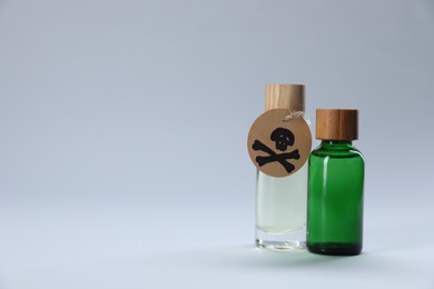 Photo of Bottles of poisons with warning sign on light grey background, space for text