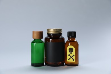 Photo of Bottles of poisons with warning sign on light grey background