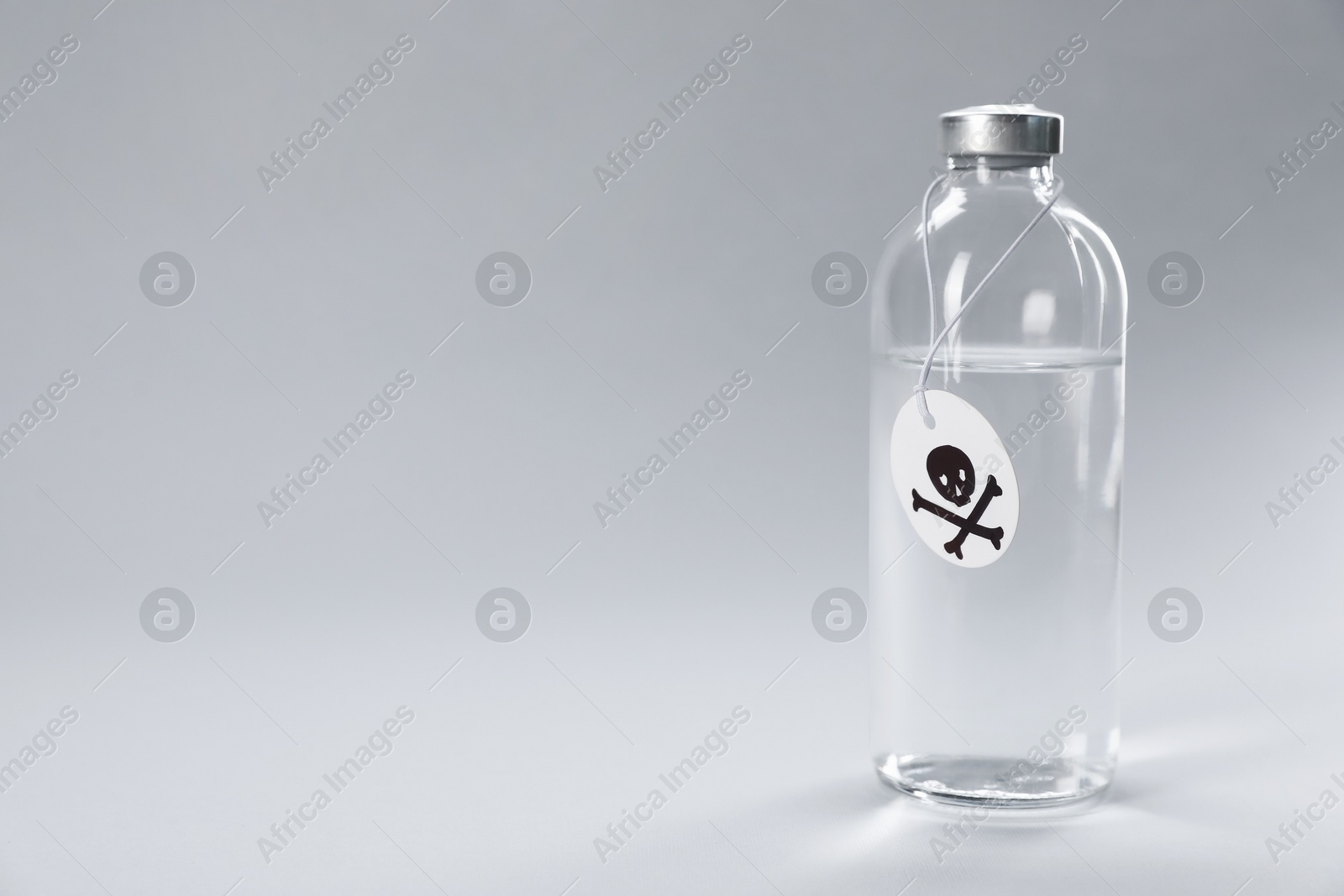 Bottle of poison with warning sign on light grey background, space for text Photo of Bottle of poison with warning sign on light grey background, space for text