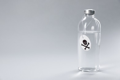 Photo of Bottle of poison with warning sign on light grey background, space for text