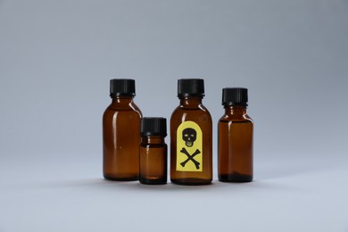 Photo of Bottles of poisons with warning sign on light grey background