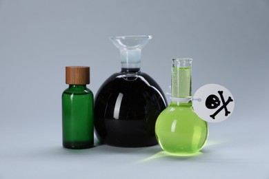 Photo of Bottles of poisons with warning sign on light grey background