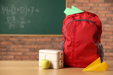 Photo of Backpack, lunchbox and apple on desk in classroom