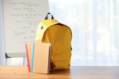 Photo of Backpack and notebooks on desk in classroom
