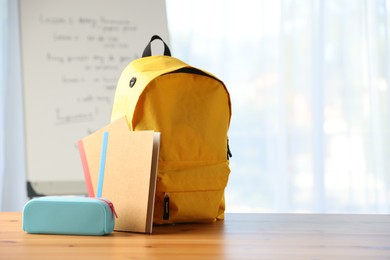 Photo of Backpack, notebooks and pencil case on desk in classroom