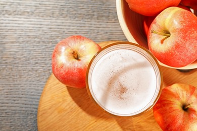 Photo of Delicious cider in glass and apples on grey wooden table, flat lay