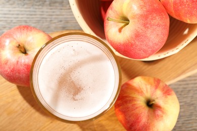 Photo of Delicious cider in glass and apples on wooden table, flat lay