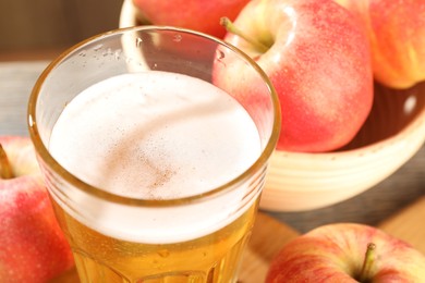 Photo of Delicious cider in glass and apples on table, closeup