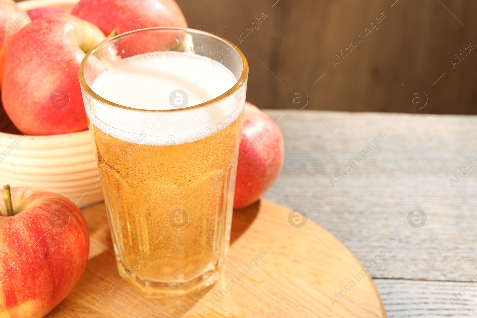 Delicious cider in glass and apples on wooden table, closeup Photo of Delicious cider in glass and apples on wooden table, closeup