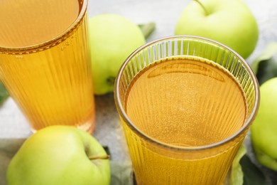 Photo of Delicious cider in glasses and apples on grey table, closeup