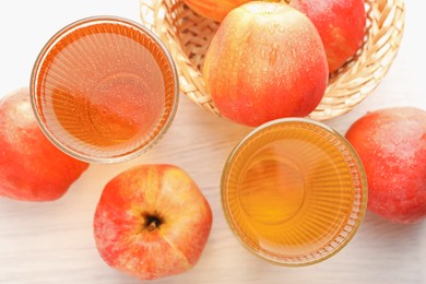 Photo of Delicious cider in glasses and red apples on white wooden table, flat lay