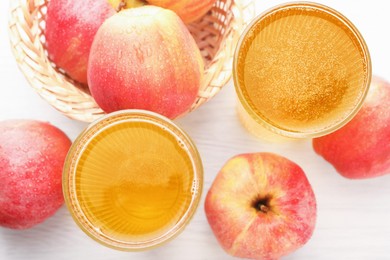 Photo of Delicious cider in glasses and red apples on white wooden table, flat lay