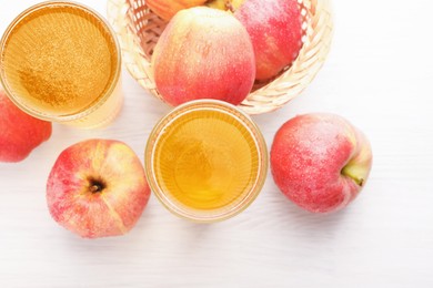 Photo of Delicious cider in glasses and red apples on white wooden table, flat lay
