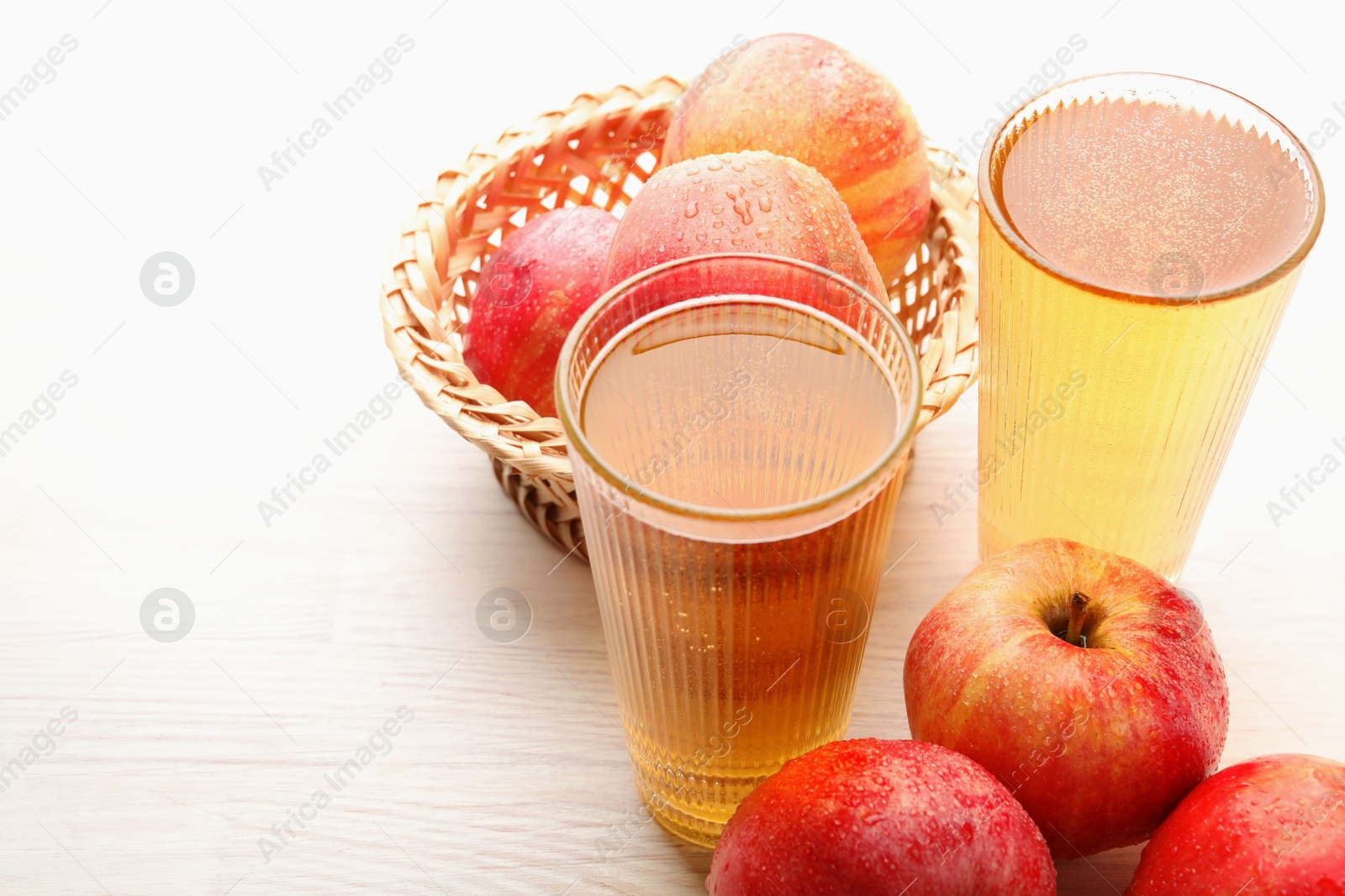 Photo of Delicious cider in glasses and red apples on white wooden table, closeup