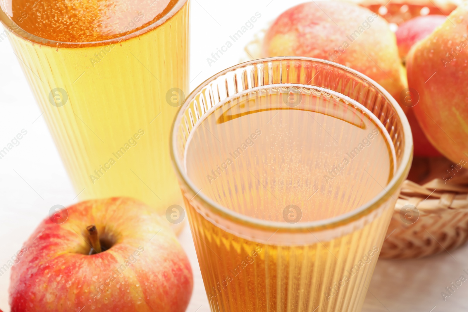 Photo of Delicious cider in glasses and red apples on white table, closeup