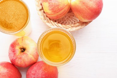 Photo of Delicious cider in glasses and red apples on white wooden table, flat lay