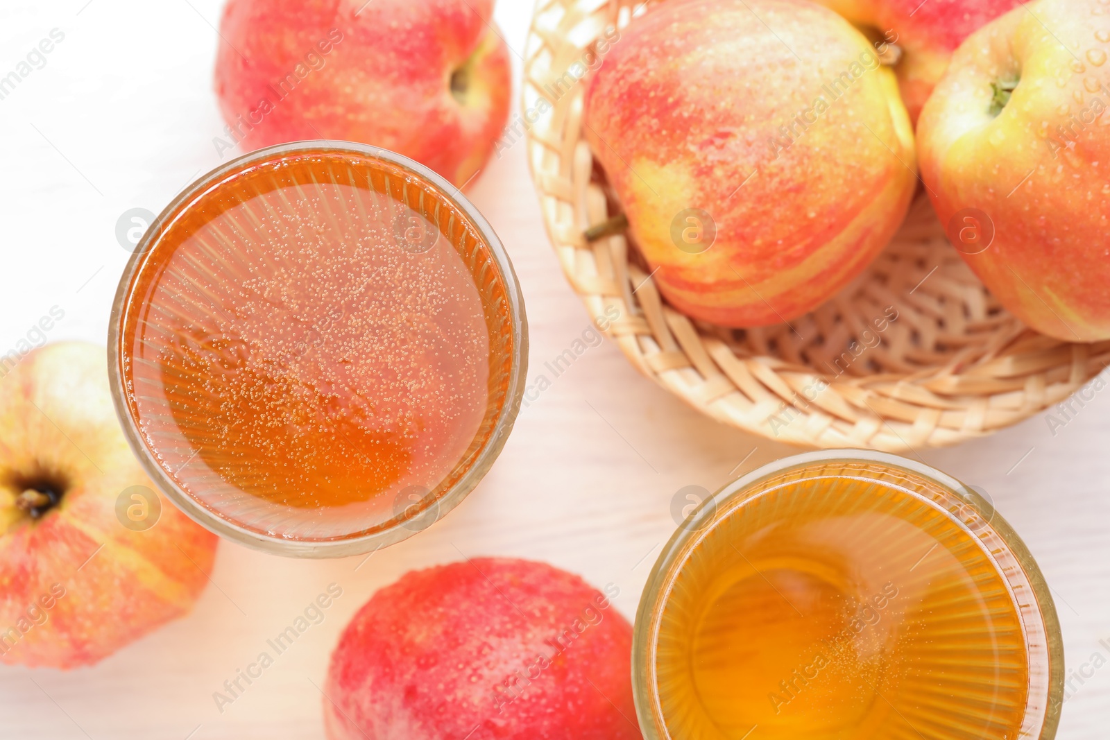 Photo of Delicious cider in glasses and red apples on white wooden table, flat lay