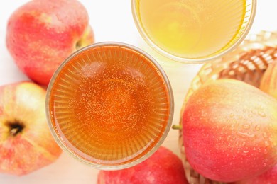Photo of Delicious cider in glasses and red apples on white table, flat lay