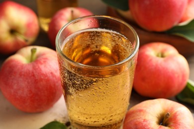 Photo of Delicious cider in glass and apples on table, closeup