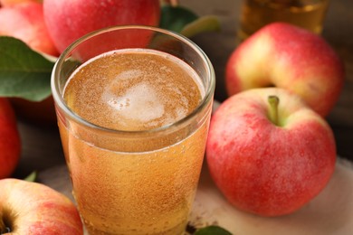 Photo of Delicious cider in glass and apples on table, closeup