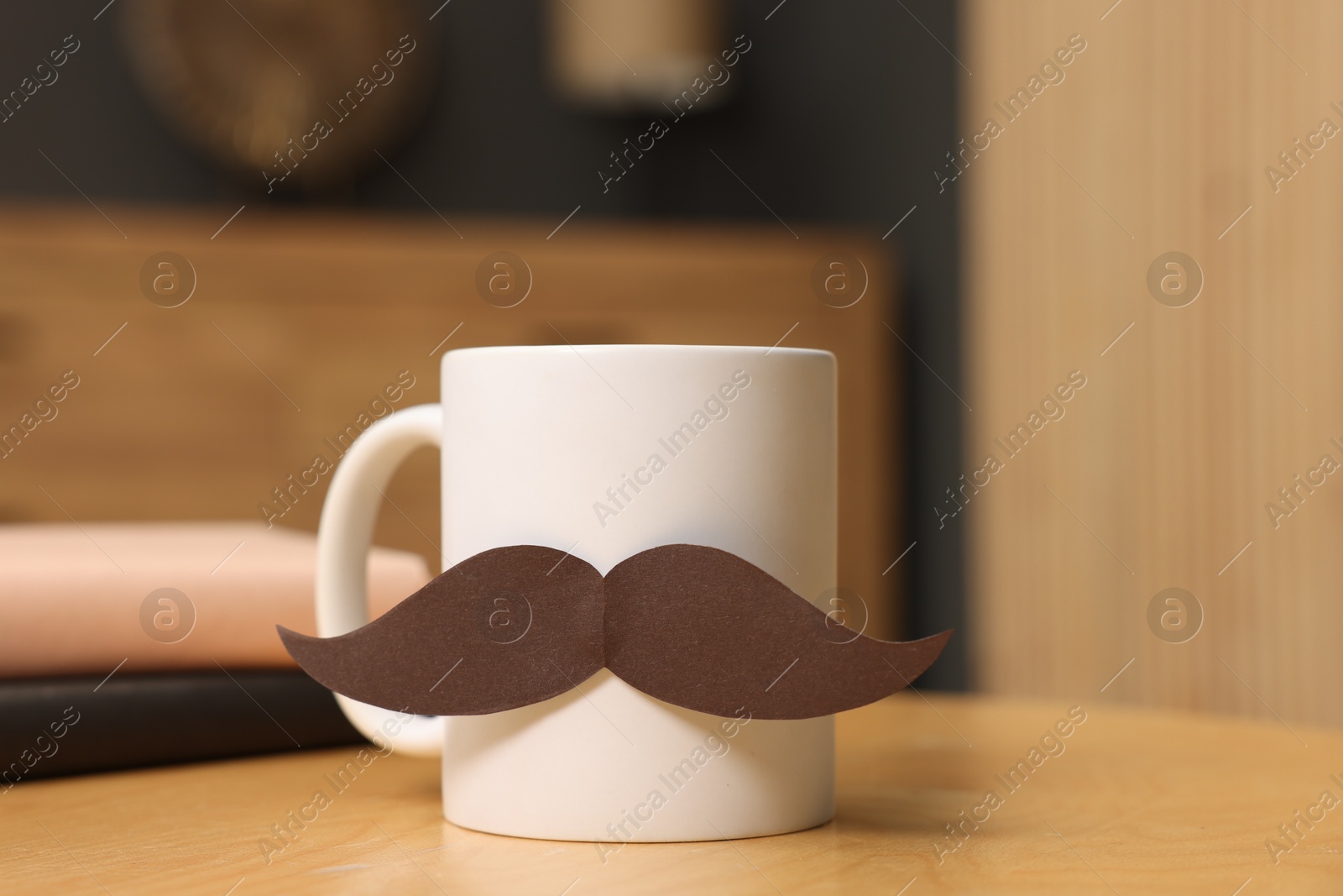 Happy Father's Day. Cup with paper moustache and books on wooden table indoors, closeup Photo of Happy Father's Day. Cup with paper moustache and books on wooden table indoors, closeup